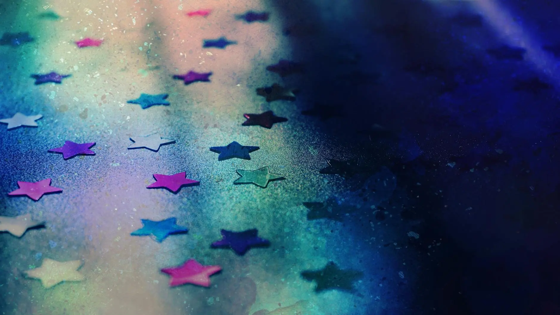 Close-up of colorful glitter stars on a vibrant blue and purple background.